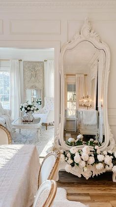 a mirror sitting on top of a wooden floor next to a white table and chairs