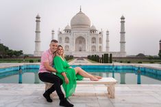 a man and woman sitting on a bench in front of the tajwa mosque