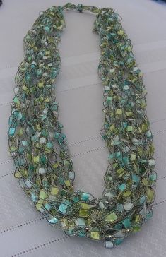 Here is a delicate pastel ladder yarn necklace in shades of green, light teal and pearlescent white - all with a sparkle of silver - for dressy or casual looks. There are 7 crocheted strands - enough for a lovely effect and yet so lightweight you hardly know you are wearing jewelry! Be sure to look at the close-up photo for color detail. It is called Ladder or Trellis Yarn because it consists of soft, woven panels suspended between contrasting or same color threads. A shiny Lurex thread fed thro Elegant Green Necklace For Beach, Elegant Green Necklace For Spring, Green Necklace For Spring Beach Occasions, Green Necklaces For Summer Parties, Handmade Green Beaded Necklace For Spring, Spring Party Green Necklaces, Handmade Green Necklaces For Spring, Ladder Yarn Necklace, Ladder Yarn