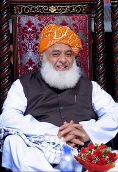 a man sitting in a chair with a white beard and orange turban on his head