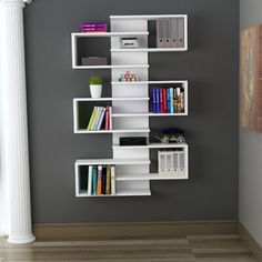 a white book shelf with books on it against a gray wall in an empty room