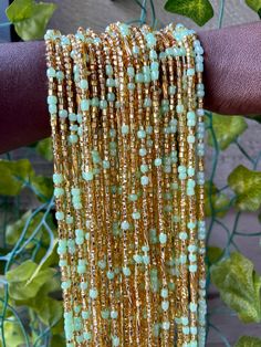 a woman's arm with gold and green beaded bracelets