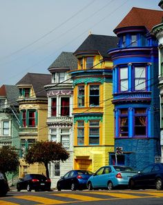 a row of multi - colored houses on the corner of a street in san francisco