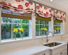 a kitchen with white cabinets and yellow flowers on the window sill, along with a sink