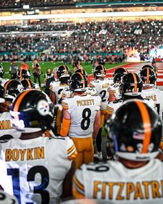 a group of football players standing next to each other in front of an audience at a game