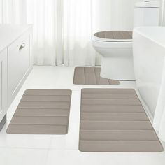 three bath mats and rugs in a white bathroom