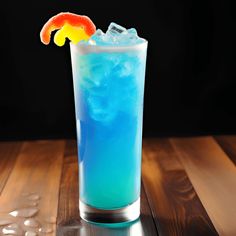 a tall glass filled with blue liquid and an orange slice