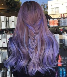 a woman with long, purple hair is seen from the back in front of a store window