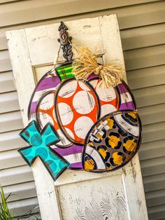 a door hanger decorated with colorful designs and a cross hanging from it's side