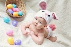 a baby wearing a bunny hat and diaper next to easter eggs