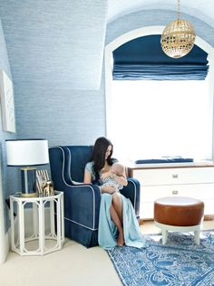 a woman sitting on a couch in a room with blue walls and carpeted floor