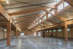 an empty warehouse with wood beams and windows on the ceiling, is shown in this image