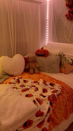 a bed covered in blankets and pillows with pumpkins on the comforter next to it