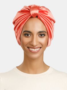 a woman wearing a pink turban smiles at the camera while standing in front of a white background