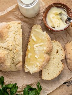 bread, butter and parsley on a piece of parchment paper next to a cup of yogurt