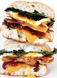 three sandwiches stacked on top of each other with cheese, bacon, and spinach