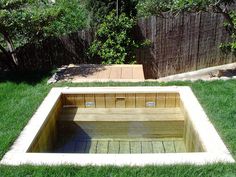 a wooden bench sitting in the middle of a lush green yard next to a fence