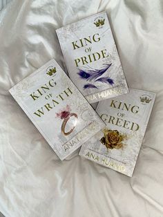 three books sitting on top of a bed next to each other in front of a white comforter