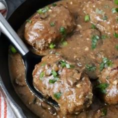 meatballs and gravy in a skillet with a spoon