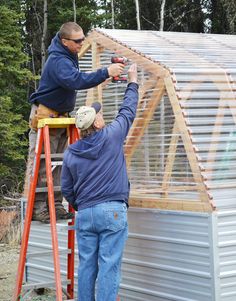 two men are working on the roof of a building with metal sheets and wood framing