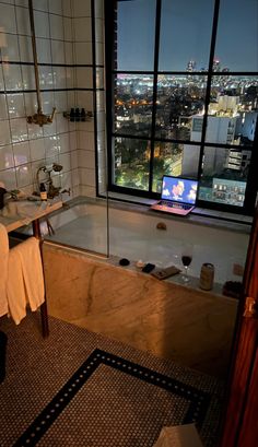 a bath tub sitting next to a window with a tv on it's side