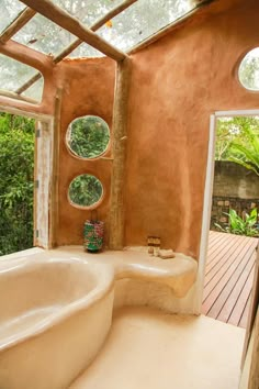 a bathroom with a large bathtub next to an open door and windows that look out onto the jungle