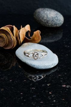 a silver ring sitting on top of a rock next to a flower and two stones