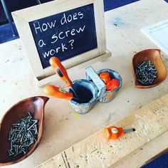 a wooden table topped with bowls filled with carrots next to a chalkboard sign that says how does a screw work?