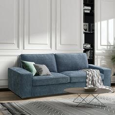 a living room with a blue couch and rugs in front of white paneled walls