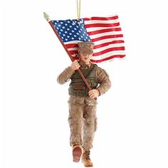 a soldier holding an american flag ornament hanging from a chain on a white background