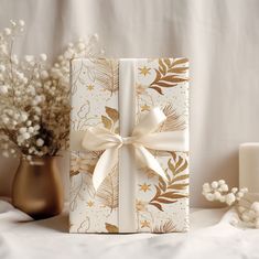 a gift wrapped in gold foil with a white ribbon