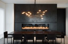 a dining room table with chairs and a fire place on the wall in front of it