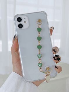 a woman is holding up her phone case with charms on the front and back of it