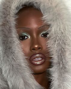 a woman wearing a fur coat and silver makeup