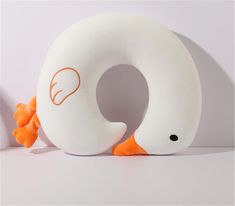 a stuffed animal with an orange nose and tail sitting in front of a white pillow