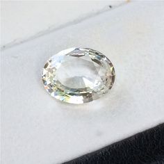 an oval cut diamond sitting on top of a white countertop next to a black piece of cloth