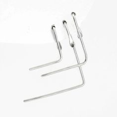 two pairs of metal hooks on a white surface