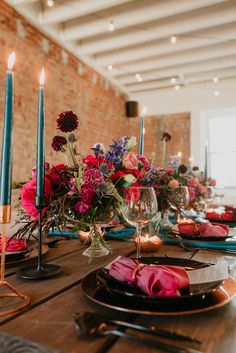 the table is set with candles, plates and flowers in vases on top of it