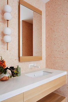 a bathroom with a sink, mirror and flowers on the counter