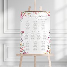 an easel with a floral seating plan on it in front of a white wall