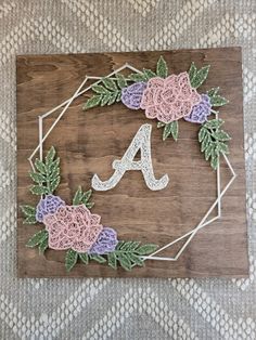 a wooden sign with crochet flowers and the letter a on it's side