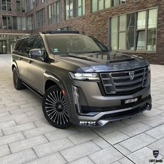 an suv is parked in front of a building with large windows and black rims