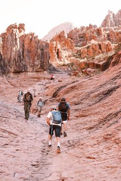 several people hiking through the desert with mountains in the background