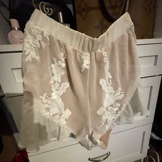 Never Worn Feminine Cream Bottoms For The Beach, Feminine Cream Bottoms For Beach, Feminine Cream Beach Bottoms, Chic Lace Trim Bottoms For Beach, Elegant White Summer Shorts, Feminine Beige Bottoms For Vacation, White Bottoms With Lace Trim For Spring, Chic Shorts With Lace Trim, Chic Spring Shorts With Lace Trim