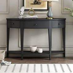 a black console table with two white vases and a painting on the wall behind it