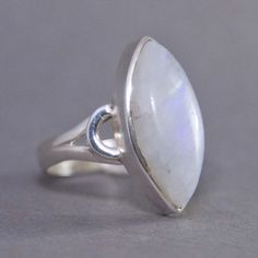 SKU: SS-048Material: 925 stamped sterling silverGemstone(s): Rainbow Moonstone (N)Gemstone Dimensions: 10 X 22 X 4 mmRing Size: US 7.5Weight: 5.9 gramsThis graceful Rainbow Moonstone cabochon ring features a marquise Rainbow Moonstone with a curved motif on its sides and a split shank band. The Rainbow Moonstone is a mostly opaque white with a subtle blue and orange fire that shows throughout the ring. Simple yet elegant! Marquise White Sterling Silver Ring, Marquise Sterling Silver Ring In White, Spiritual Moonstone Ring With Large Stone In Sterling Silver, Spiritual Sterling Silver Moonstone Ring With Large Stone, Spiritual Large Stone Moonstone Ring In Sterling Silver, Spiritual Large Stone Sterling Silver Moonstone Ring, Sterling Silver Oval Cabochon Moonstone Ring, Oval Cabochon Moonstone Ring In Sterling Silver, Sterling Silver Moonstone Ring With Large Stone