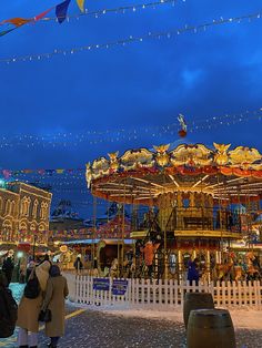 people are standing around in front of a merry - go - round at night time