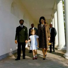 a woman in a leopard print coat and dress walks with two children