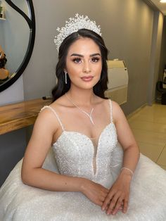 a woman wearing a tiara sitting in a chair with her hands on her hips