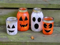 three mason jars decorated with pumpkin faces and jack - o'- lantern faces are sitting on a bench